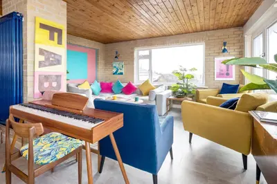 a living room with a piano and a couch at Sunset Beach House Porthleven in Porthleven