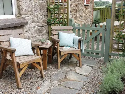 a patio with two chairs and a table and a fence at The Old Farmhouse in Michaelstow