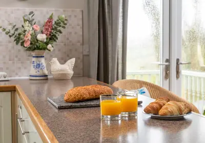 a kitchen counter with two glasses of orange juice and croissants at The Old Farmhouse in Michaelstow