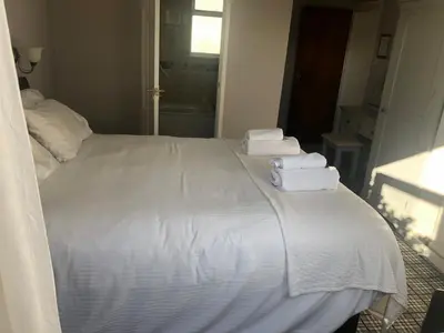 a bedroom with a white bed with towels on it at Southcote Accommodation in Tintagel