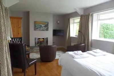 a bedroom with a bed and chairs and a fireplace at Southcote Accommodation in Tintagel