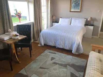 a bedroom with a bed and a table and a window at Southcote Accommodation in Tintagel