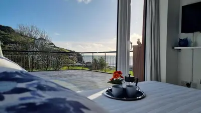 a room with a table with a view of a balcony at May View - Luxury Sea View Apartment - Millendreath, Looe in Looe