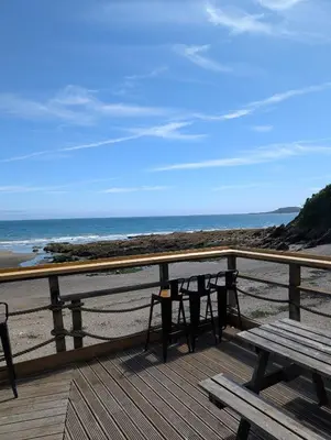 a deck with a picnic table and chairs on the beach at May View - Luxury Sea View Apartment - Millendreath, Looe in Looe
