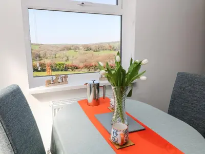 a dining room table with a vase with flowers on it at The View in Bodmin