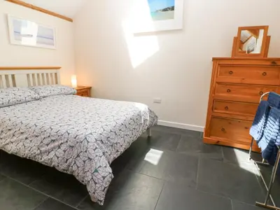 a bedroom with a bed and a dresser at Godolphin Barn in Helston