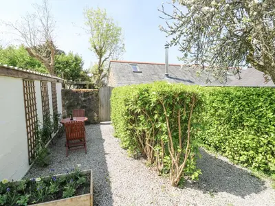 a garden with a chair and a hedge at Godolphin Barn in Helston