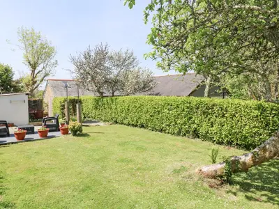 a backyard with a hedge and a lawn at Godolphin Barn in Helston