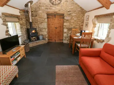 a living room with a red couch and a fireplace at Godolphin Barn in Helston