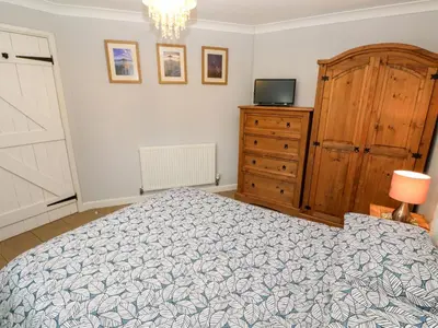 a bedroom with a bed and a dresser and a television at Tregonning Lodge in Helston