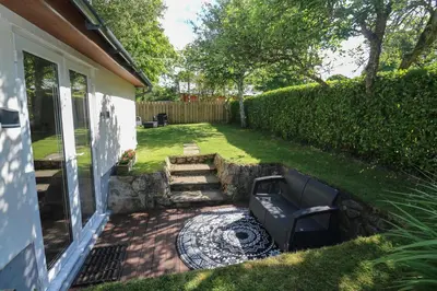 a backyard with a bench and a stone wall at Tregonning Lodge in Helston
