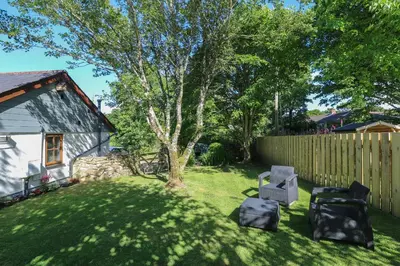 a yard with two chairs and a fence at Tregonning Lodge in Helston
