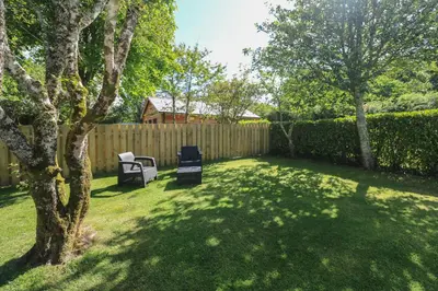 a yard with two chairs and a fence at Tregonning Lodge in Helston