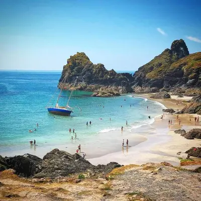 a group of people on a beach with a boat in the water at 3.9. Tudor Court in Hayle