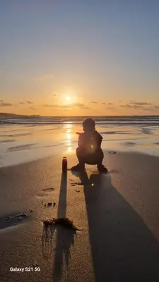 a person sitting on the beach watching the sunset at 3.9. Tudor Court in Hayle