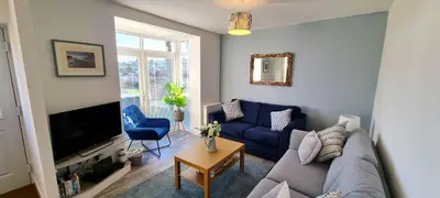 a living room with a blue couch and a tv at Parkside in Perranporth