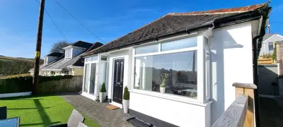 a white house with large windows in a yard at Parkside in Perranporth