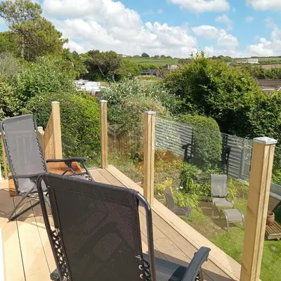 a deck with a television and chairs on it at Curlews Cottage - House with 3 bedrooms and garden - walking distance to the beach in Perranporth