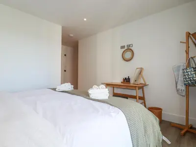 a bedroom with a white bed and a table at 33 Cliff Edge in Newquay