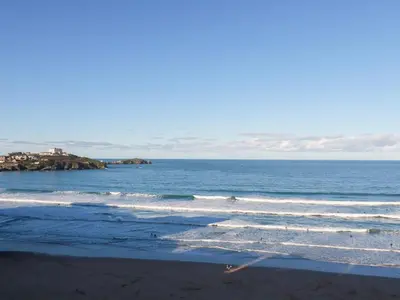 a beach with waves and a building in the distance at 33 Cliff Edge in Newquay