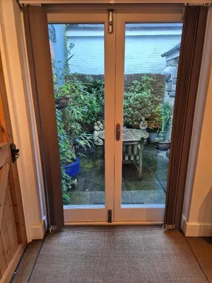 a sliding glass door with a view of a garden at Tregarthen Cottage - tranquil self-contained room near Looe offering easy parking right outside with EV point in Looe