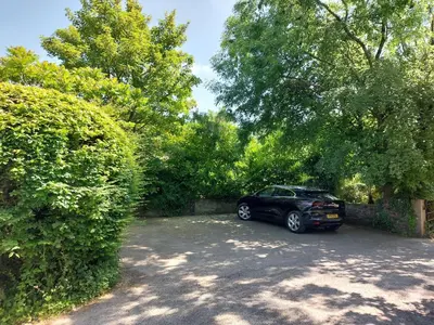 a car parked in a parking lot next to a hedge at Tregarthen Cottage - tranquil self-contained room near Looe offering easy parking right outside with EV point in Looe