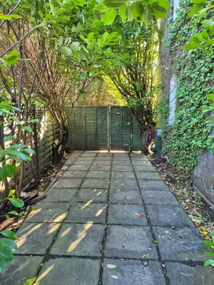 a stone walkway with trees and a green fence at Tregarthen Cottage - tranquil self-contained room near Looe offering easy parking right outside with EV point in Looe