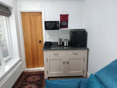 a room with a kitchen with a counter with a microwave at Tregarthen Cottage - tranquil self-contained room near Looe offering easy parking right outside with EV point in Looe