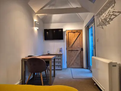 a room with a desk and a barn door at Tregarthen Cottage - tranquil self-contained room near Looe offering easy parking right outside with EV point in Looe