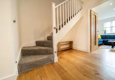 a living room with stairs and a blue couch at Huckleberry - Premium, Hot Tub, x2 Parking, Farm Shop Next door, Private Cornish Lane in Newquay