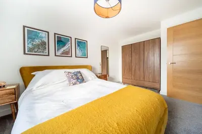 a bedroom with a large bed with a yellow blanket at Huckleberry - Premium, Hot Tub, x2 Parking, Farm Shop Next door, Private Cornish Lane in Newquay