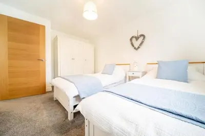 a bedroom with two beds and a heart sign on the wall at Huckleberry - Premium, Hot Tub, x2 Parking, Farm Shop Next door, Private Cornish Lane in Newquay