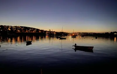 a group of boats sitting in the water at night at Honeycomb Lodge - Holiday Home 5 min from Padstow in Padstow