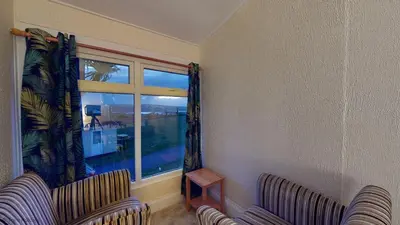 a living room with two chairs and a window at A18 Bojago, Riviere Towans in Hayle