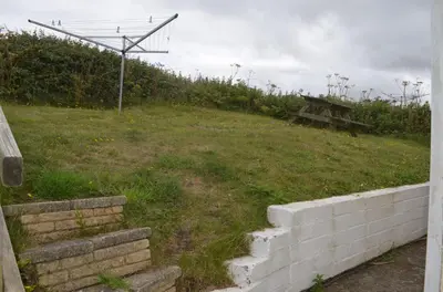 a grassy field with a fence and a picnic table at A18 Bojago, Riviere Towans in Hayle