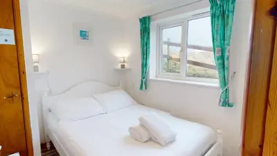 a white bed in a room with a window at A19 Eatondale, Riviere Towans in Hayle
