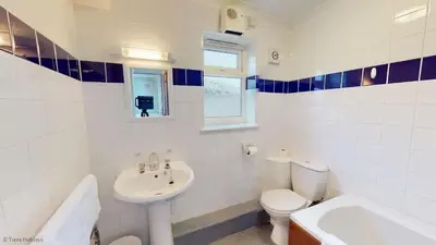 a white bathroom with a toilet and a sink at A19 Eatondale, Riviere Towans in Hayle
