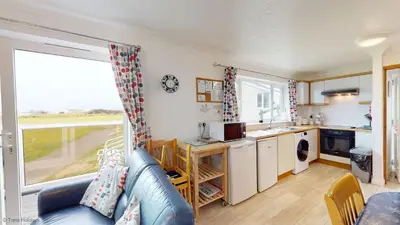 a living room with a blue couch and a kitchen at A19 Eatondale, Riviere Towans in Hayle