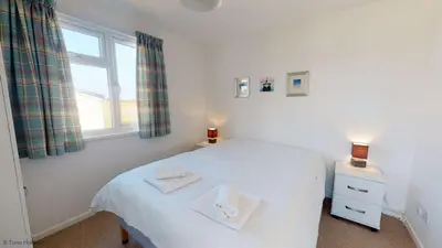 a bedroom with a white bed and a window at A21 Solano, Riviere Towans in Hayle