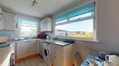 a kitchen with a washing machine and a window at A21 Solano, Riviere Towans in Hayle