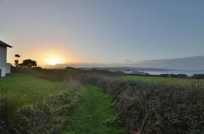a field of grass with the sunset in the background at B11 Treague, Riviere Towans in Hayle