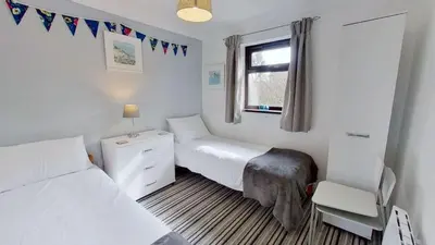 a bedroom with two beds and a desk and a window at B04 Beachcroft B4, Riviere Towans in Hayle