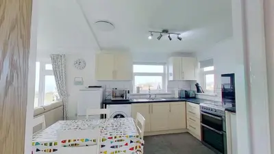 a kitchen with white cabinets and a table and a table and a table at B04 Beachcroft B4, Riviere Towans in Hayle