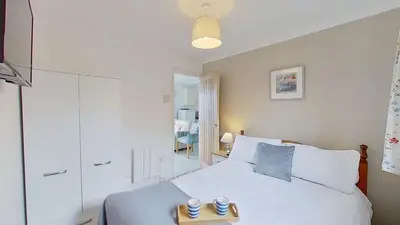 a bedroom with a white bed with two cups on a tray at B04 Beachcroft B4, Riviere Towans in Hayle