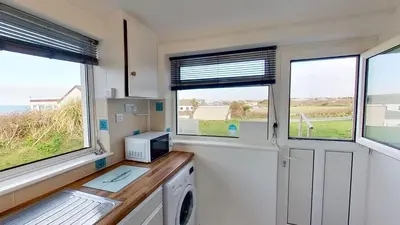 a kitchen with two windows and a washing machine at B25 Trezaren, Riviere Towans in Hayle