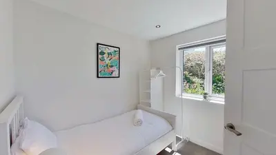 a white room with a bed and a window at B27 The Lair, Riviere Towans in Hayle