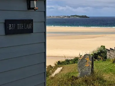 a house and a beach with a sign for bay the liar at B27 The Lair, Riviere Towans in Hayle