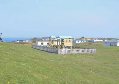 a fence in a field with houses in the background at B38 Delamar, Riviere Towans in Hayle