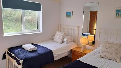 a bedroom with two beds and a window at B37 Ebb Tide, Riviere Towans in Hayle