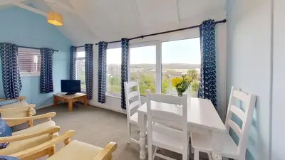 a dining room with a table and chairs and windows at B14 Amulree, Riviere Towans in Hayle
